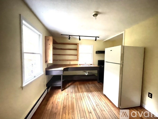 A room with wooden floors and a white refrigerator.