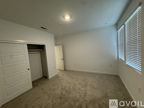 A room with a carpeted floor, a door, and a window with blinds.