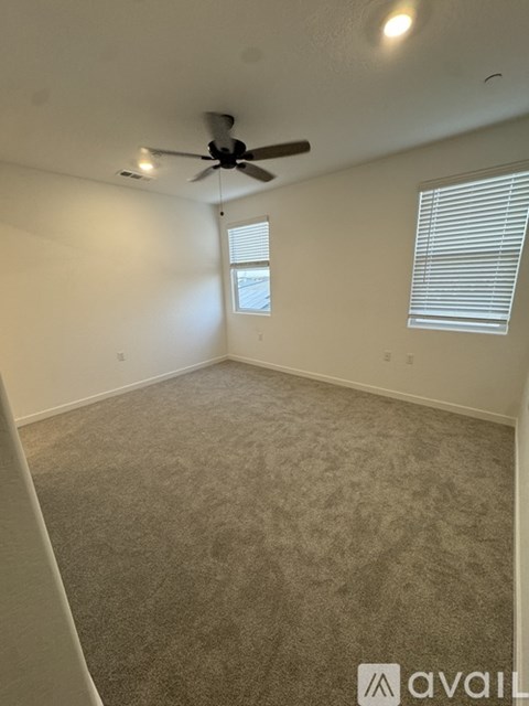 A room with a ceiling fan and carpeted floor.