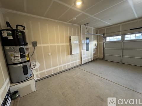 A garage with a white wall and a black fridge.