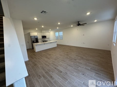 A spacious room with a ceiling fan and a kitchen area with a microwave and oven.