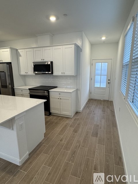 A kitchen with white cabinets and a black countertop.