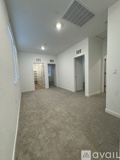 A carpeted room with a doorway leading to another room.