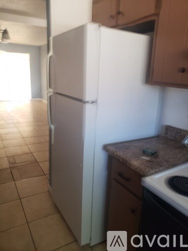 A white refrigerator in a kitchen with brown cabinets.