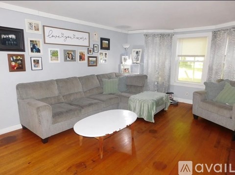 A living room with a grey couch, a white coffee table, and pictures on the wall.