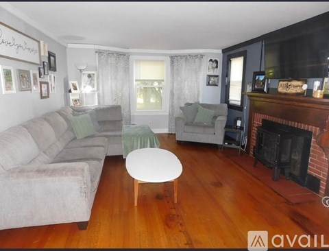 A living room with a grey couch, a white coffee table, and a fireplace.