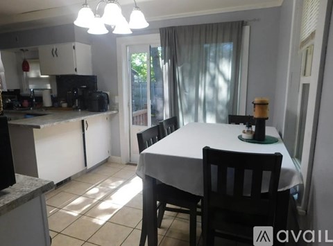 A dining room with a table set for two and a kitchen area.