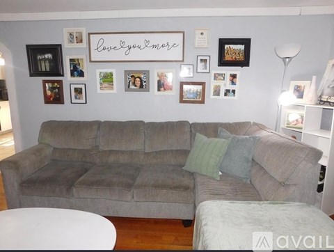 A grey couch with a white table in front of it.