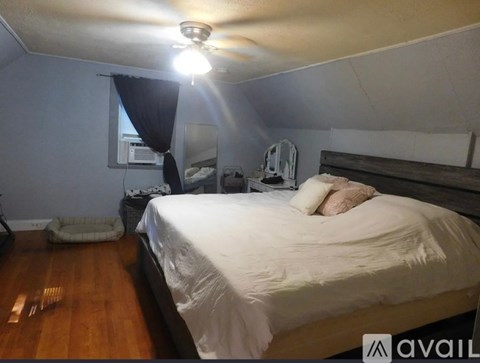 A bedroom with a bed, a fan, and a window with curtains.