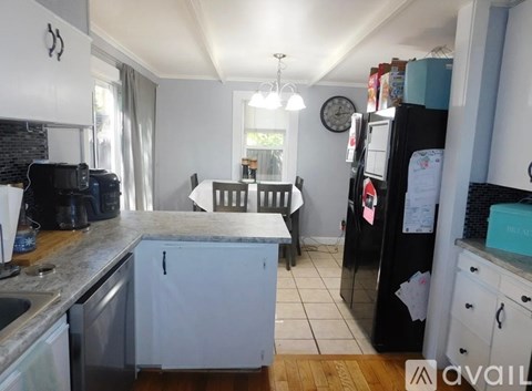 A kitchen with a black fridge and white cabinets.