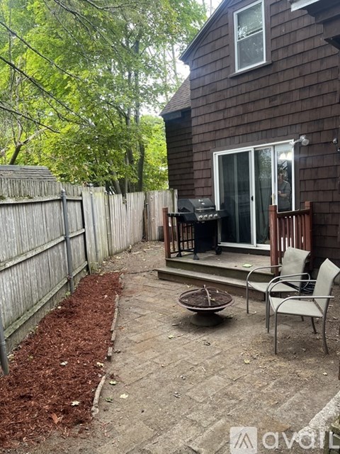 A backyard with a wooden fence, a patio table with chairs, and a fire pit.