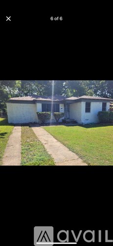 A white house with a brown roof and a green lawn in front.