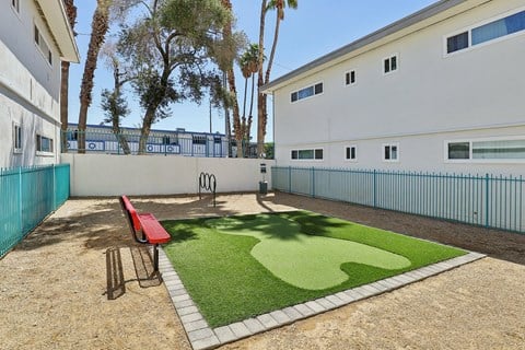 A small playground with a red bench and a green artificial lawn.