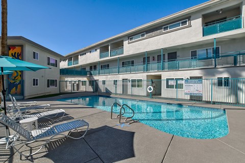 A pool area with chairs and a building in the background.