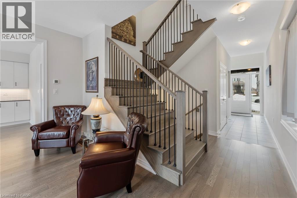 A living room with a brown leather chair and a brown leather ottoman in front of a staircase.