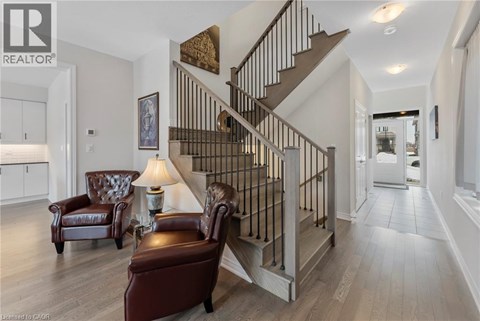 A living room with a brown leather chair and a brown leather ottoman in front of a staircase.