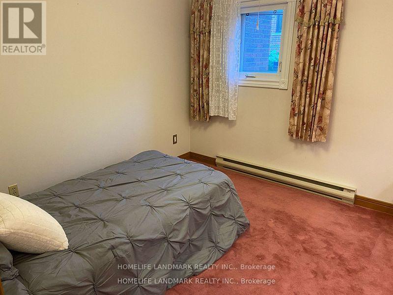 A bedroom with a bed covered in a grey comforter and a window with curtains.