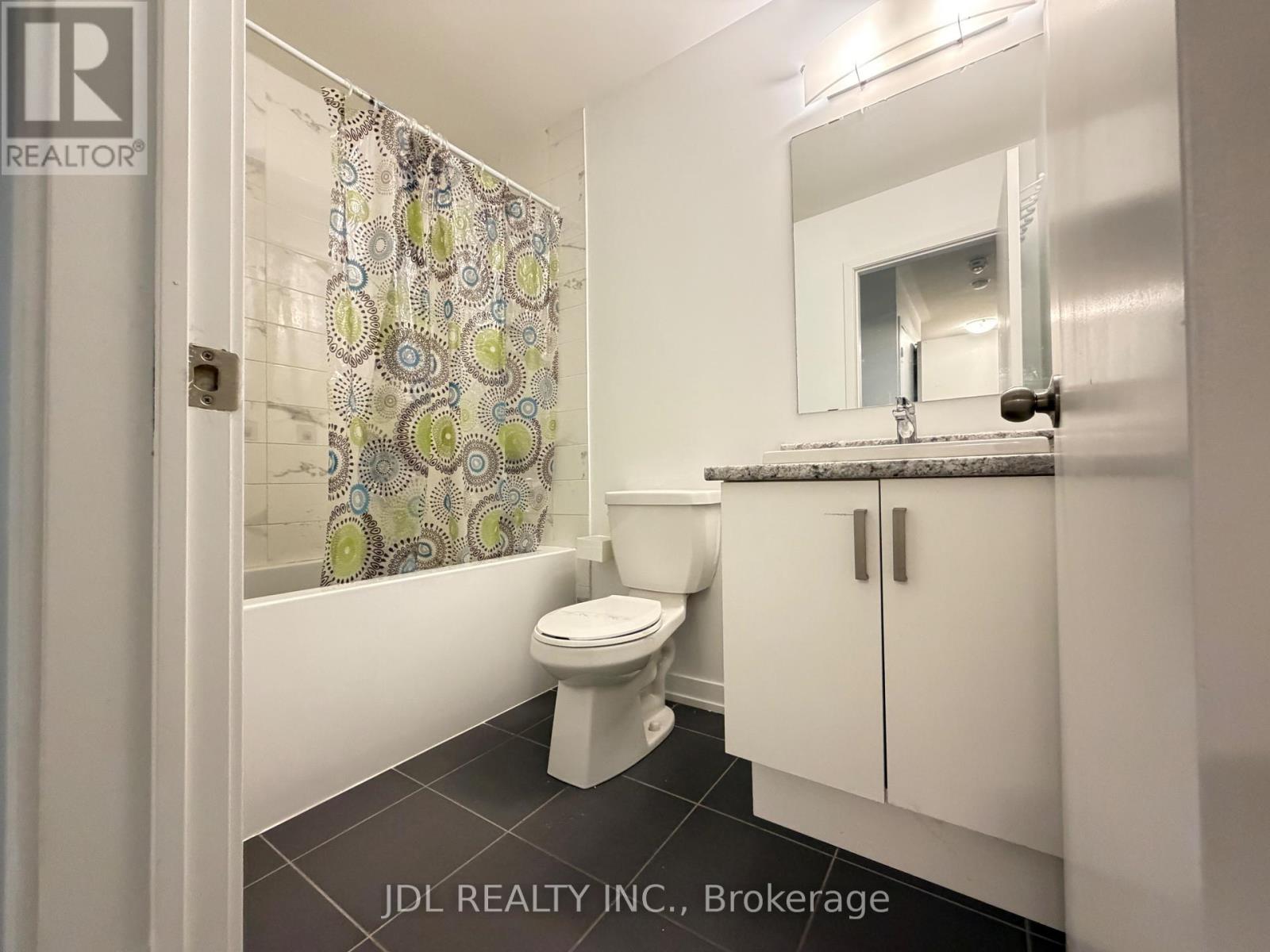 A white toilet in a small bathroom with a patterned shower curtain.