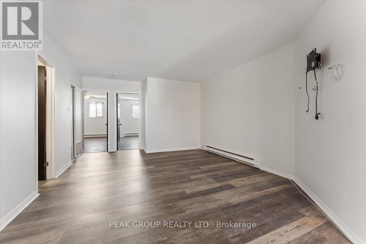 A spacious room with wooden flooring and white walls, part of a property managed by Peak Group Realty LTD.