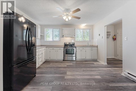 A kitchen with a black refrigerator and white cabinets.