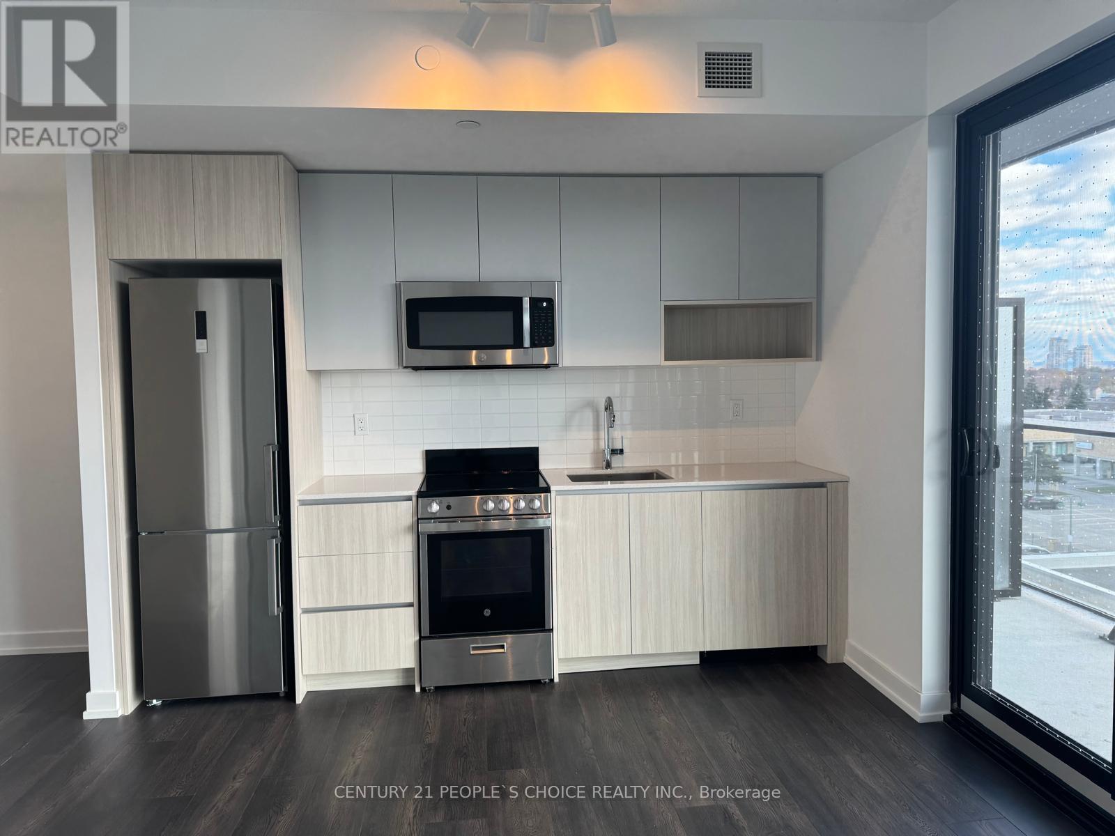 A modern kitchen with a stainless steel refrigerator and a built-in oven.
