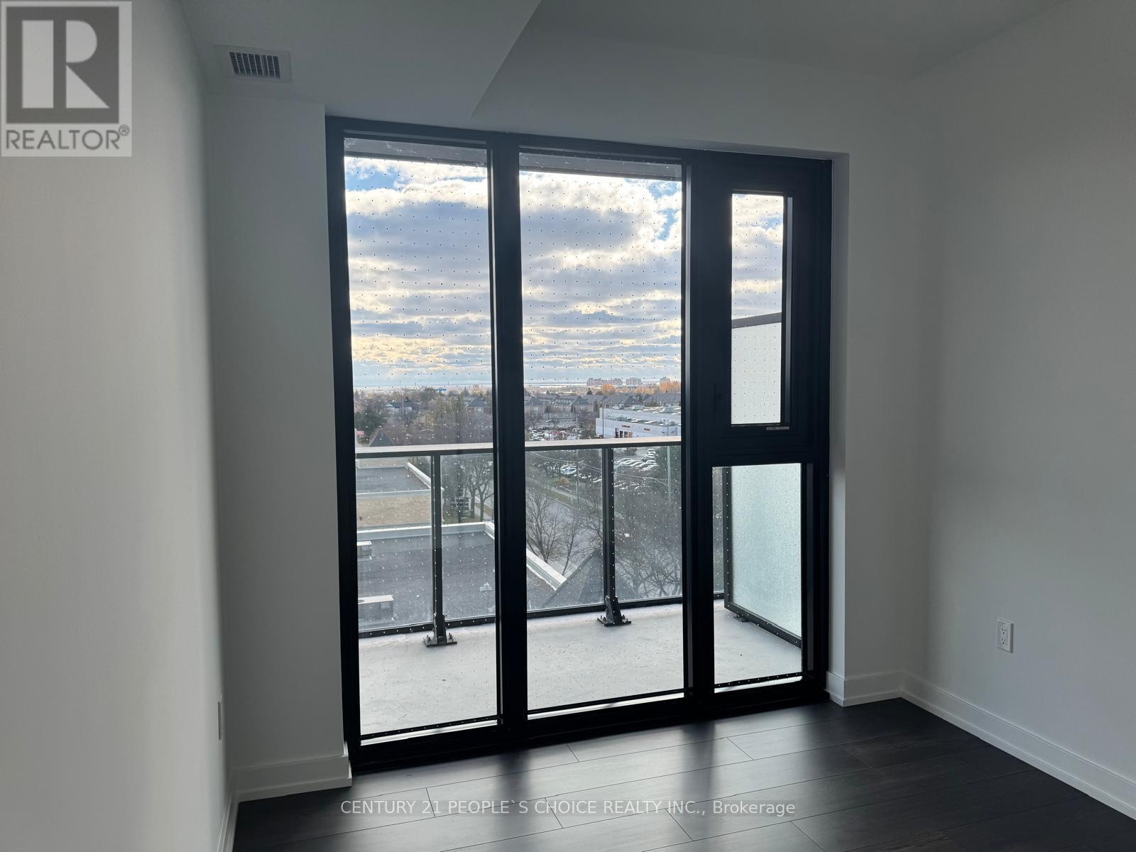 A room with a view of a parking lot through a large glass door.