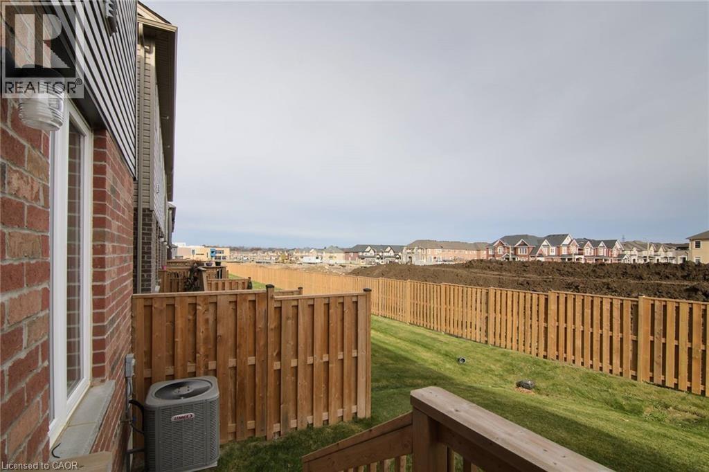 A view from a balcony overlooking a wooden fence and a grassy area.