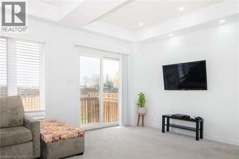 A living room with a couch, a chair, a small table, and a television mounted on the wall.