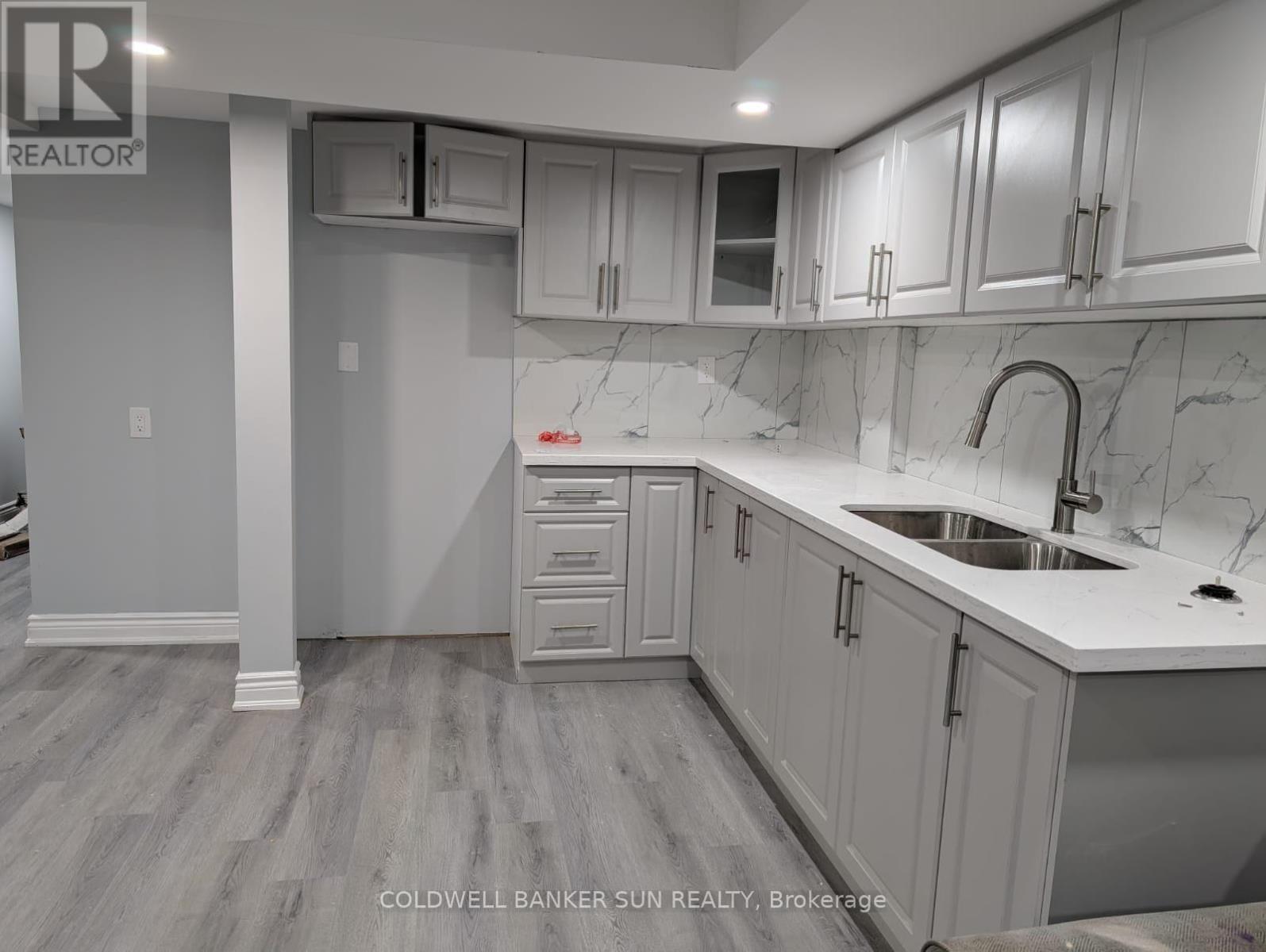 A kitchen with white cabinets and a marble countertop.