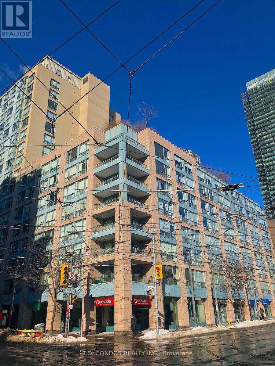 A tall building with many windows and balconies is in the foreground with a blue sky in the background.