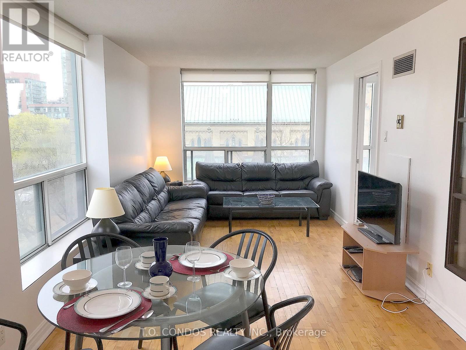 A living room with a black couch and a glass table with plates and glasses on it.