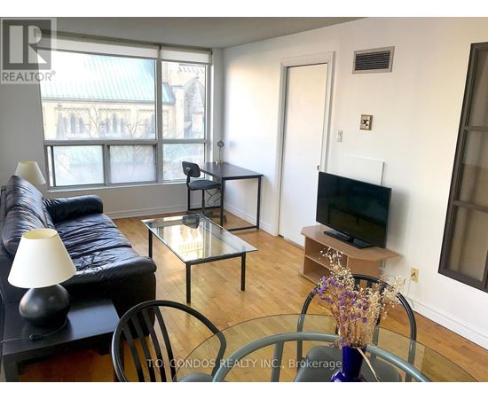A living room with a black couch and a glass table with plates and glasses on it.