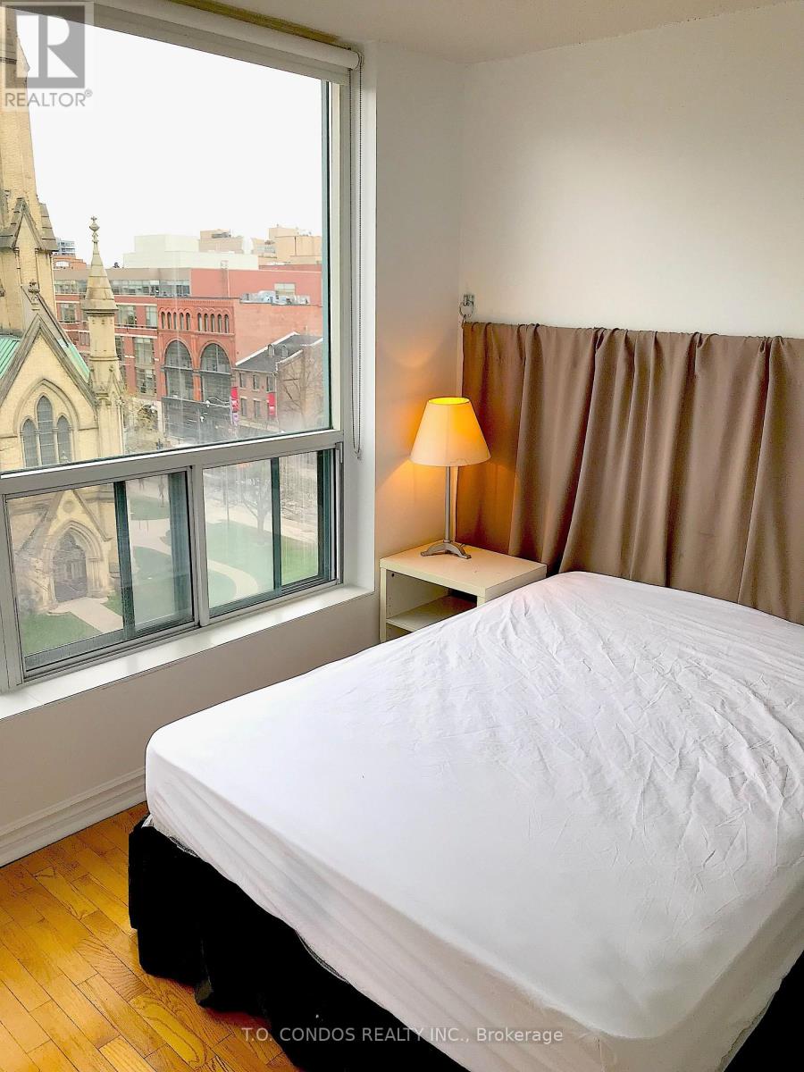 A bedroom with a large bed and a window overlooking a cityscape.