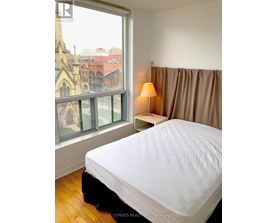 A bedroom with a large bed and a window overlooking a cityscape.