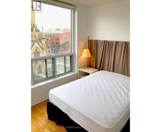 A bedroom with a large bed and a window overlooking a cityscape.