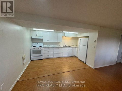 A kitchen with white cabinets and appliances in a room with wooden floors.