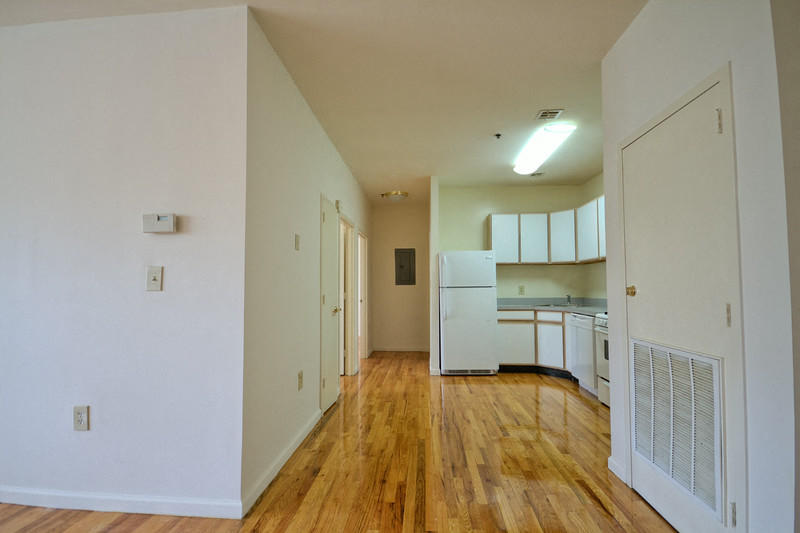 hallway leading into kitchen with wooden and white cabinets