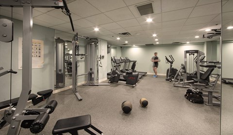 A gym with a variety of equipment and a person standing in the background.