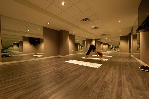 A woman is practicing yoga in a spacious room with wooden floors.