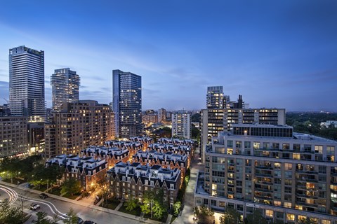 A cityscape at dusk with a mix of modern and traditional buildings.