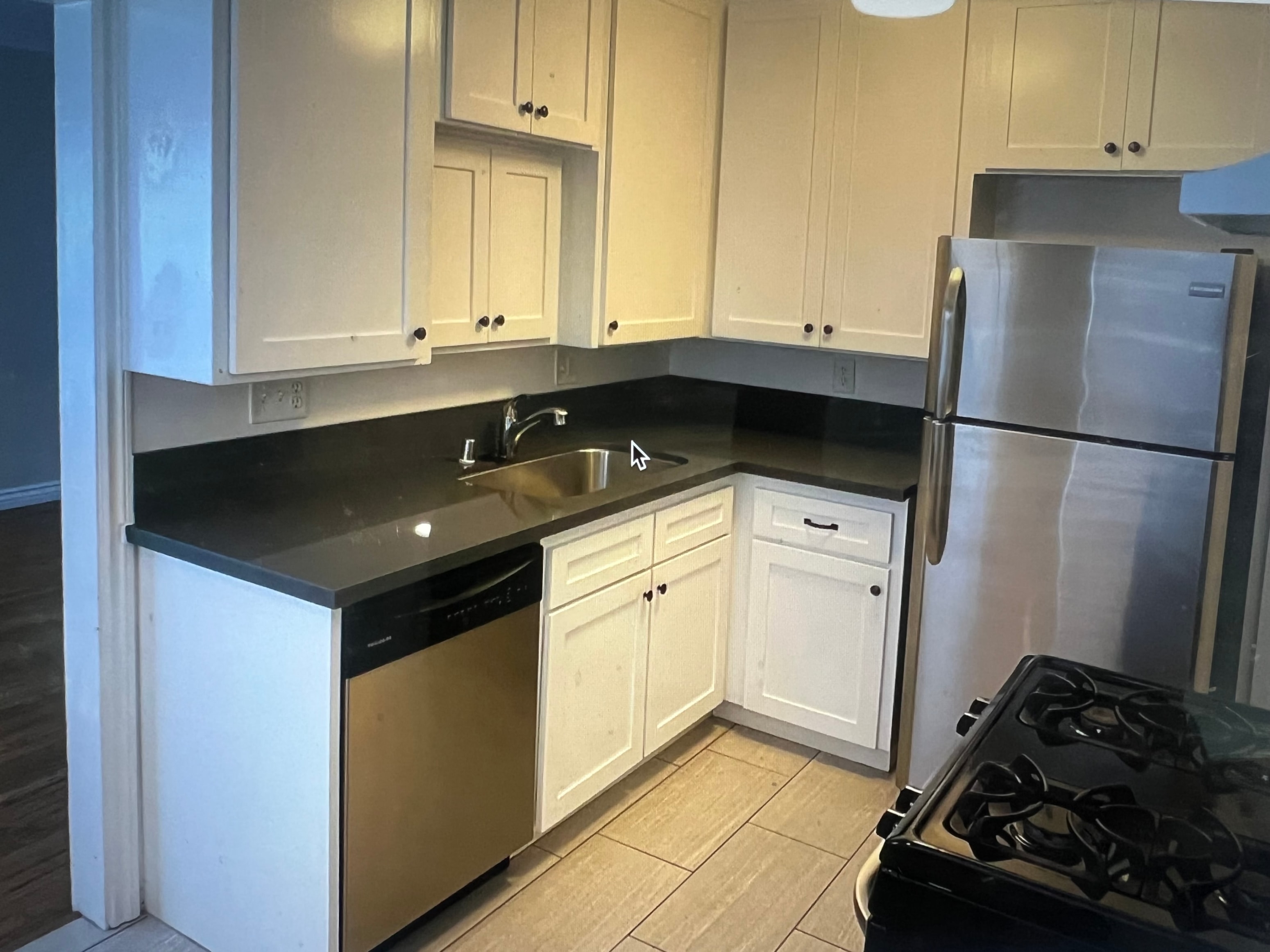 A kitchen with white cabinets and black countertops.