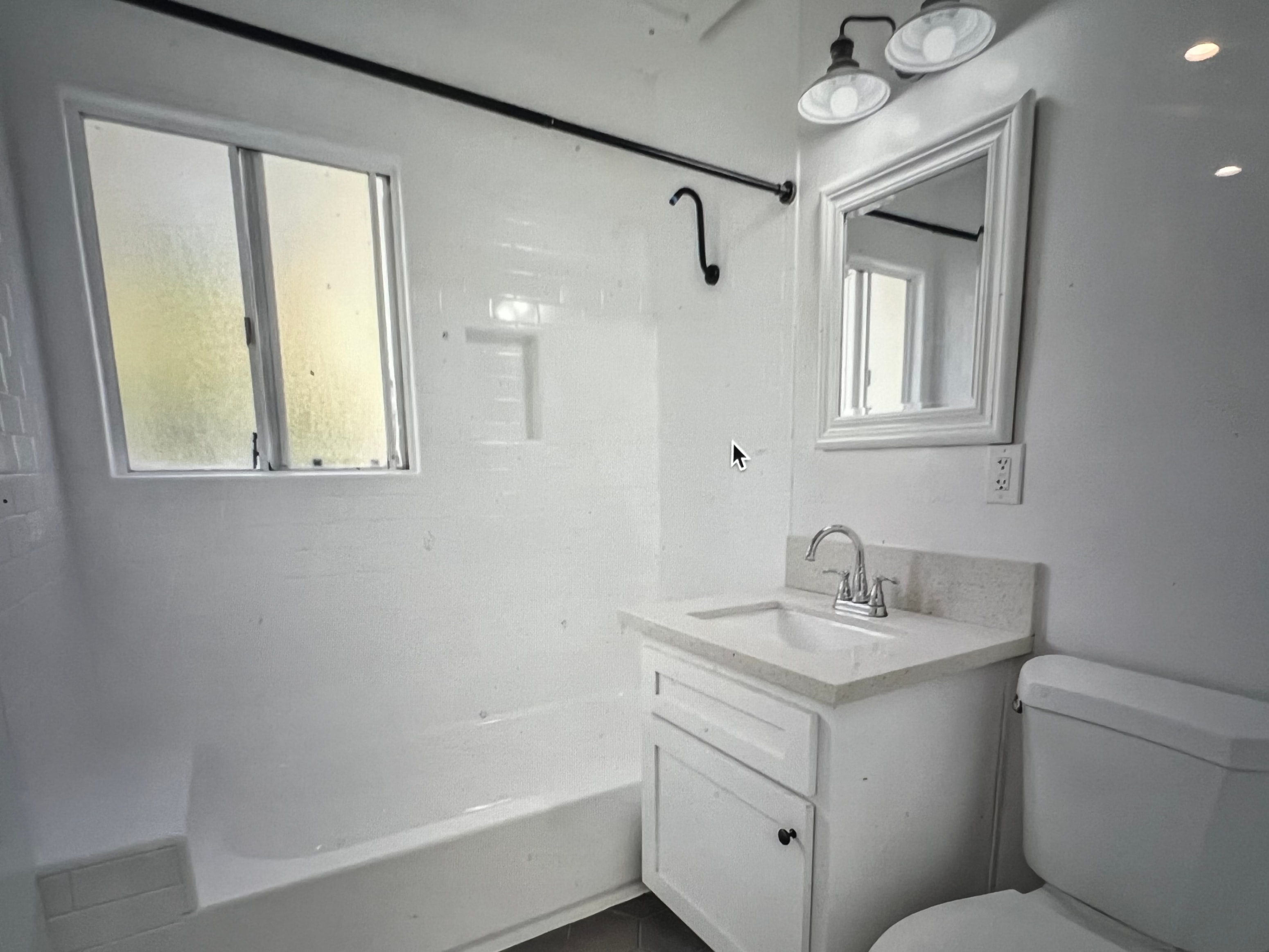 A white bathroom with a sink, mirror, and bathtub.