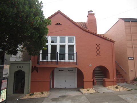 A red brick house with a white window and a grey garage door.