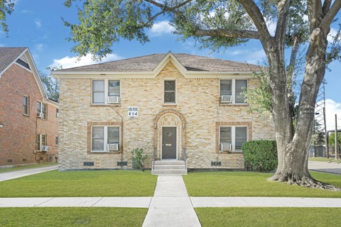 A brick house with a tree in front.