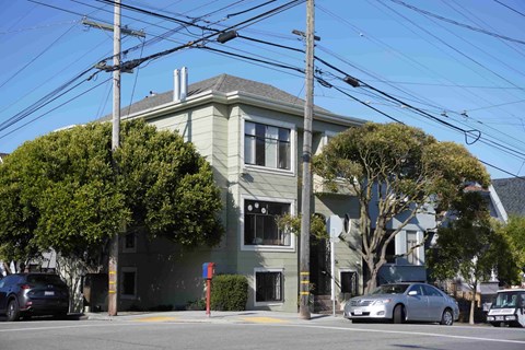 A grey two-story house with a tree in front.