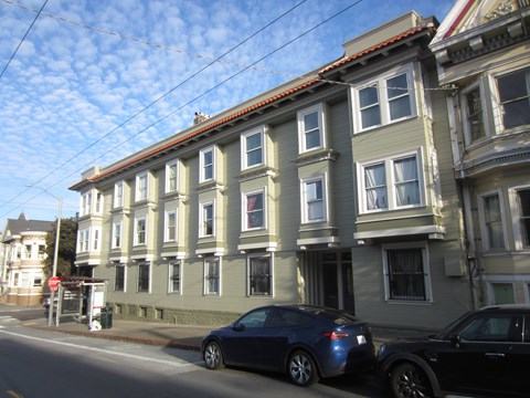 A row of houses with cars parked in front.