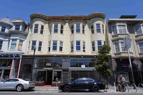 A black car is parked in front of a building with a sign that says "FIT CAFE".