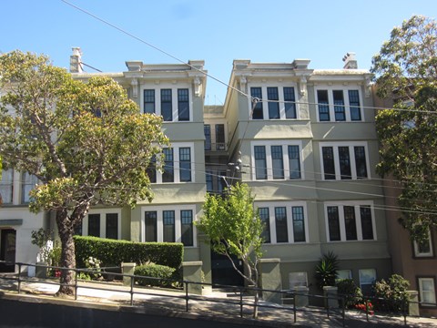 A row of houses with trees in front.