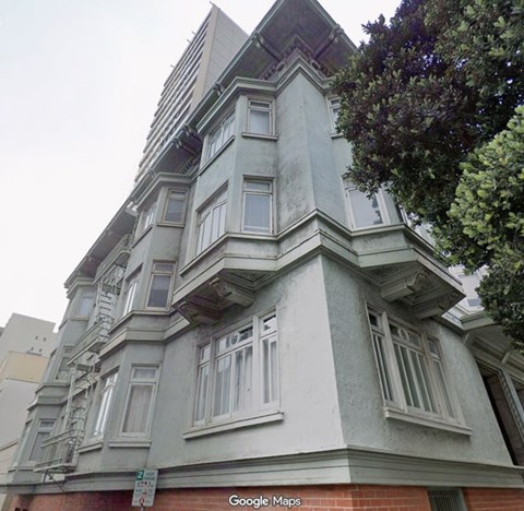 A building with a grey facade and a tree in front of it.