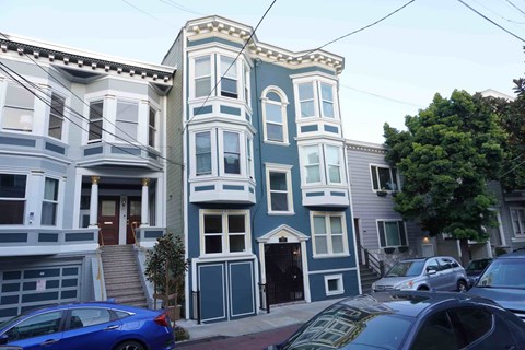 A blue car is parked in front of a house.